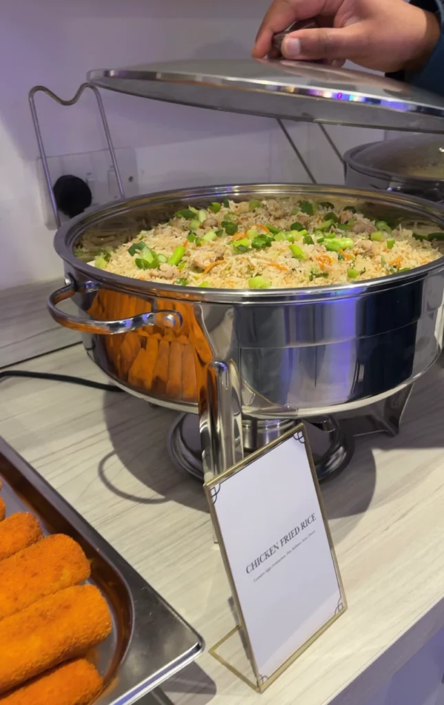A professional catering chafing dish filled with hot Sri Lankan fried rice for a buffet.